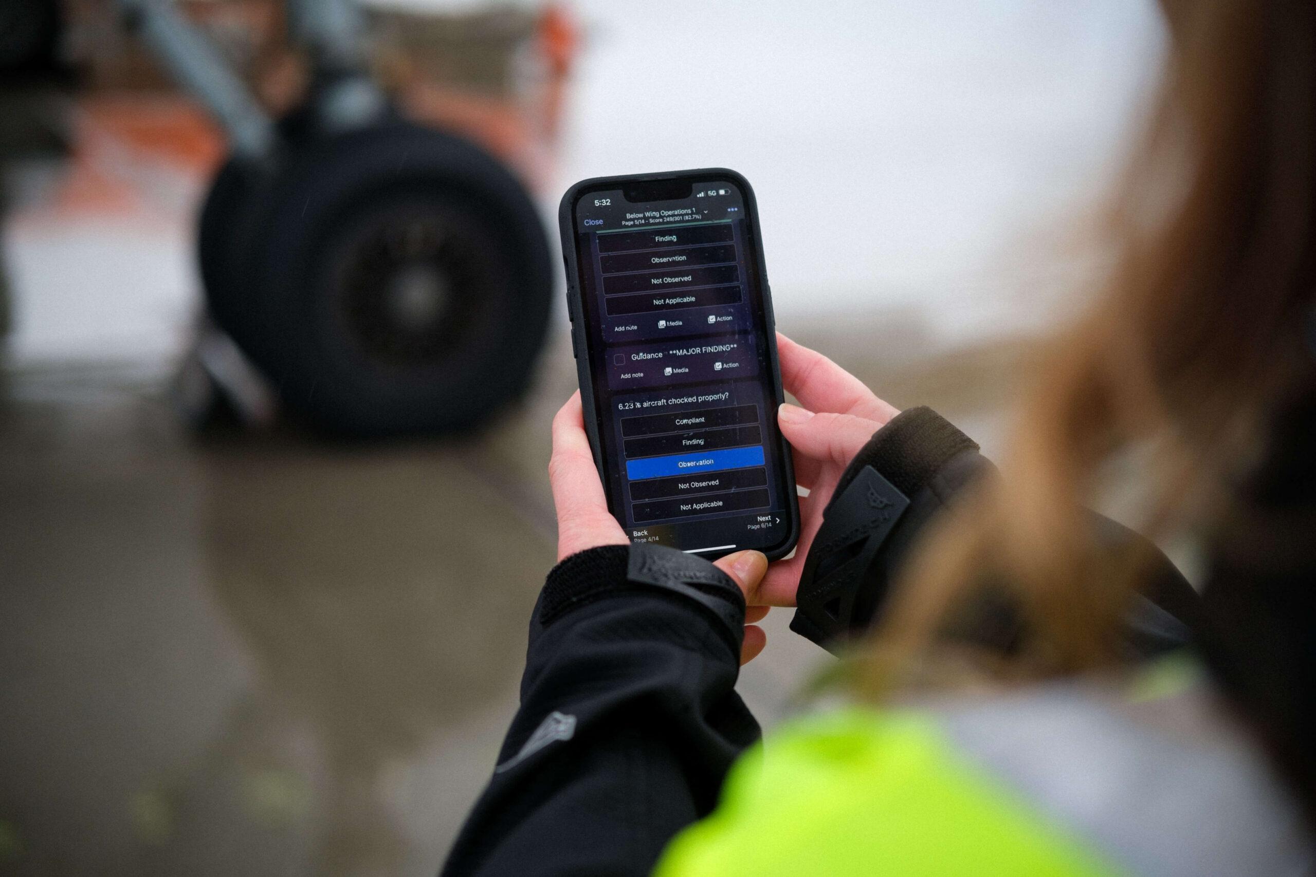 Aircraft Inspector using a digital checklist with a mobile phone to check on an aircraft