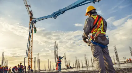 Ein Vorarbeiter kontrolliert, ob die zuvor im Toolbox-Talk besprochenen Themen bei den Arbeiten auf der Baustelle berücksichtigt werden.