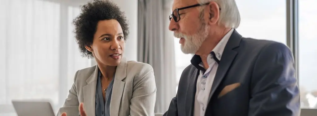 two organization leaders talking about company strategies and documenting them using corporate governance software on laptop