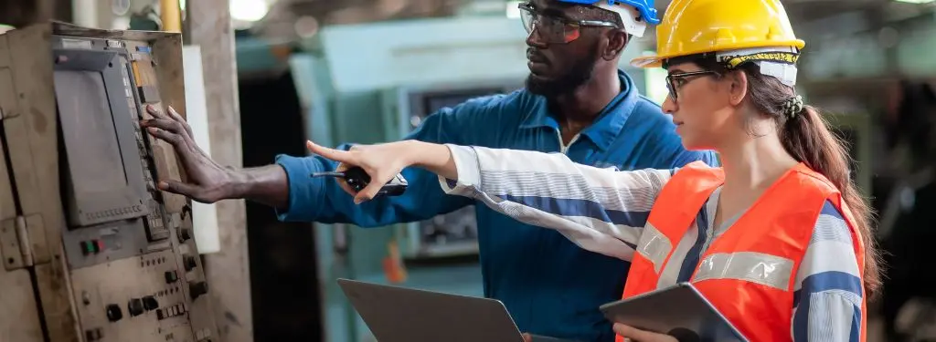 a safety officer training a new employee with the help of a compliance training software on a tablet and a laptop