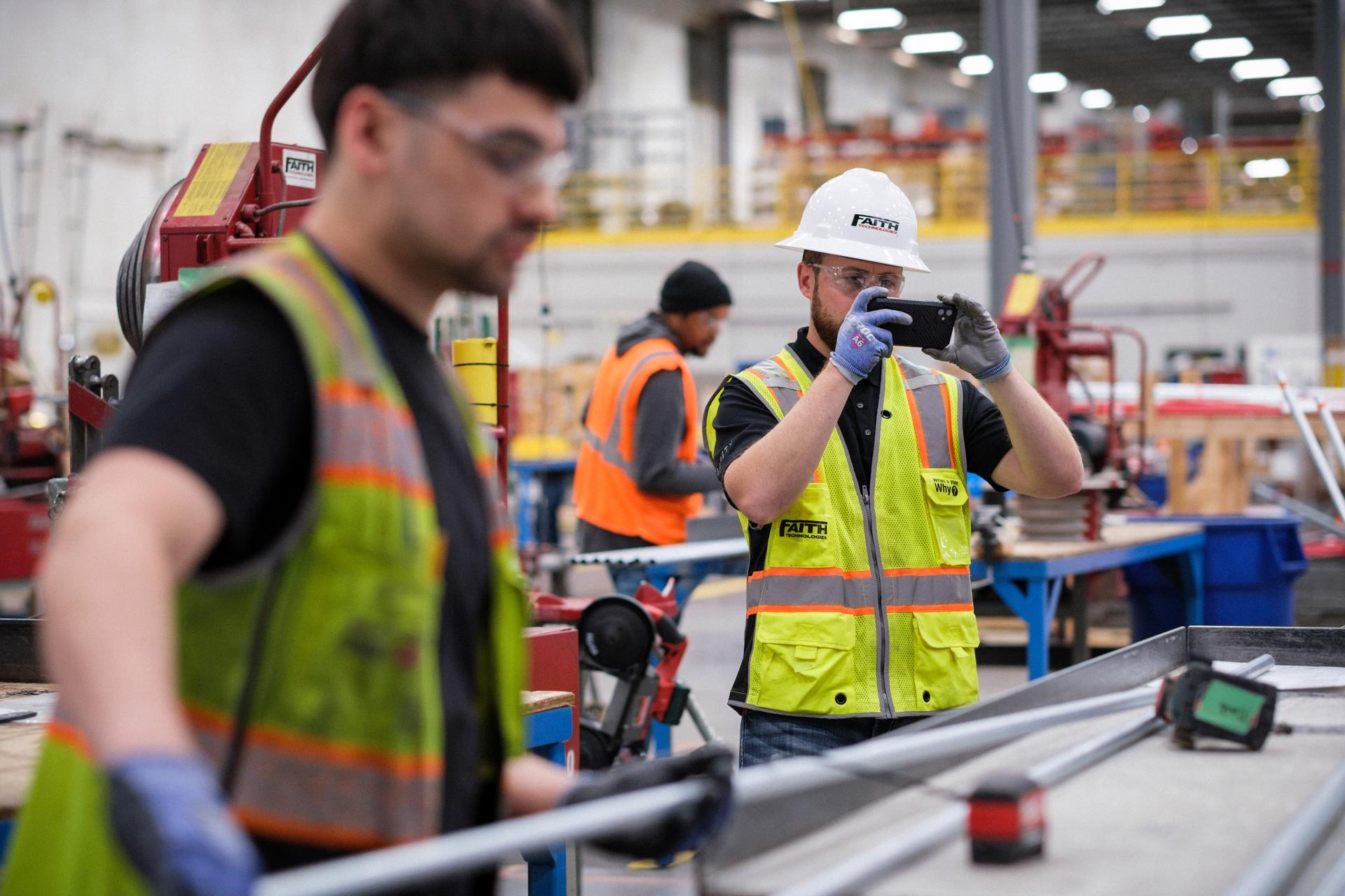 Industry worker capturing a photo of metal pipes