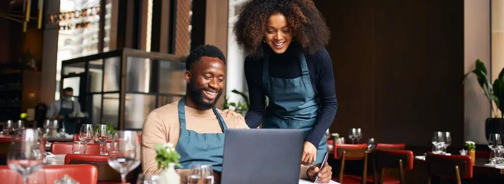 restaurant workers using a venue management software on a laptop