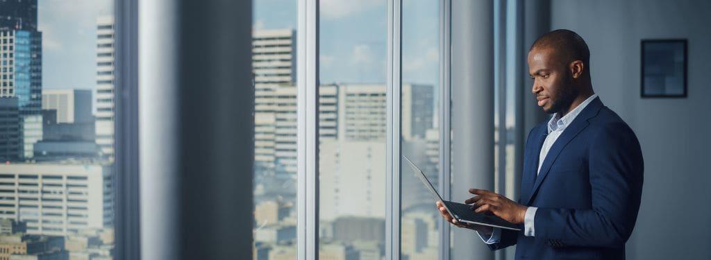 man using an iot monitoring software while standing by the window||Domotz IoT Monitoring Software||Ubidots IoT Monitoring Software|Bosch IoT Suite IoT Monitoring Software|||